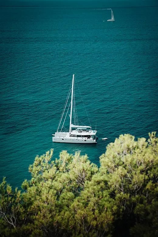 Crewed catamaran at anchor in a calm Mediterranean bay
